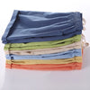 A stack of multi-colored kids cotton-linen summer shorts in various pastel shades.