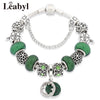Silver crystal charm bracelet featuring green leaf and floral accents with intricate metalwork.