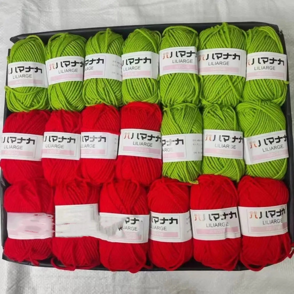 A pack of 12 skeins of various colored acrylic yarn including green, red, and white, packaged in a black box.