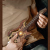 A person holds a wooden miniature guitar model kit, showing the detailed buildable puzzle craft for music lovers.