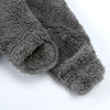 A close-up of a gray, fuzzy baby bear fleece hooded romper with a zipper.