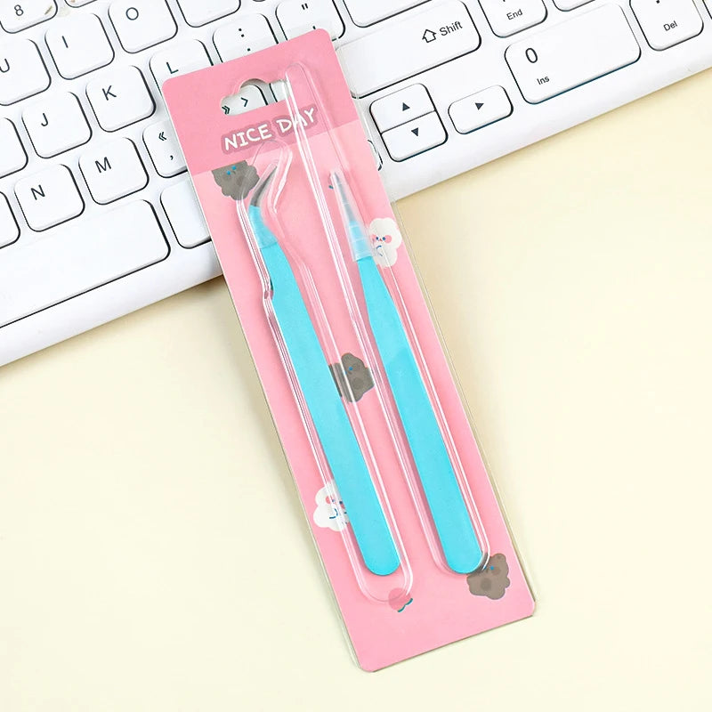 A pink packaging box holds a pair of blue precision stainless steel tweezers for nail art and makeup, resting on a white lapt