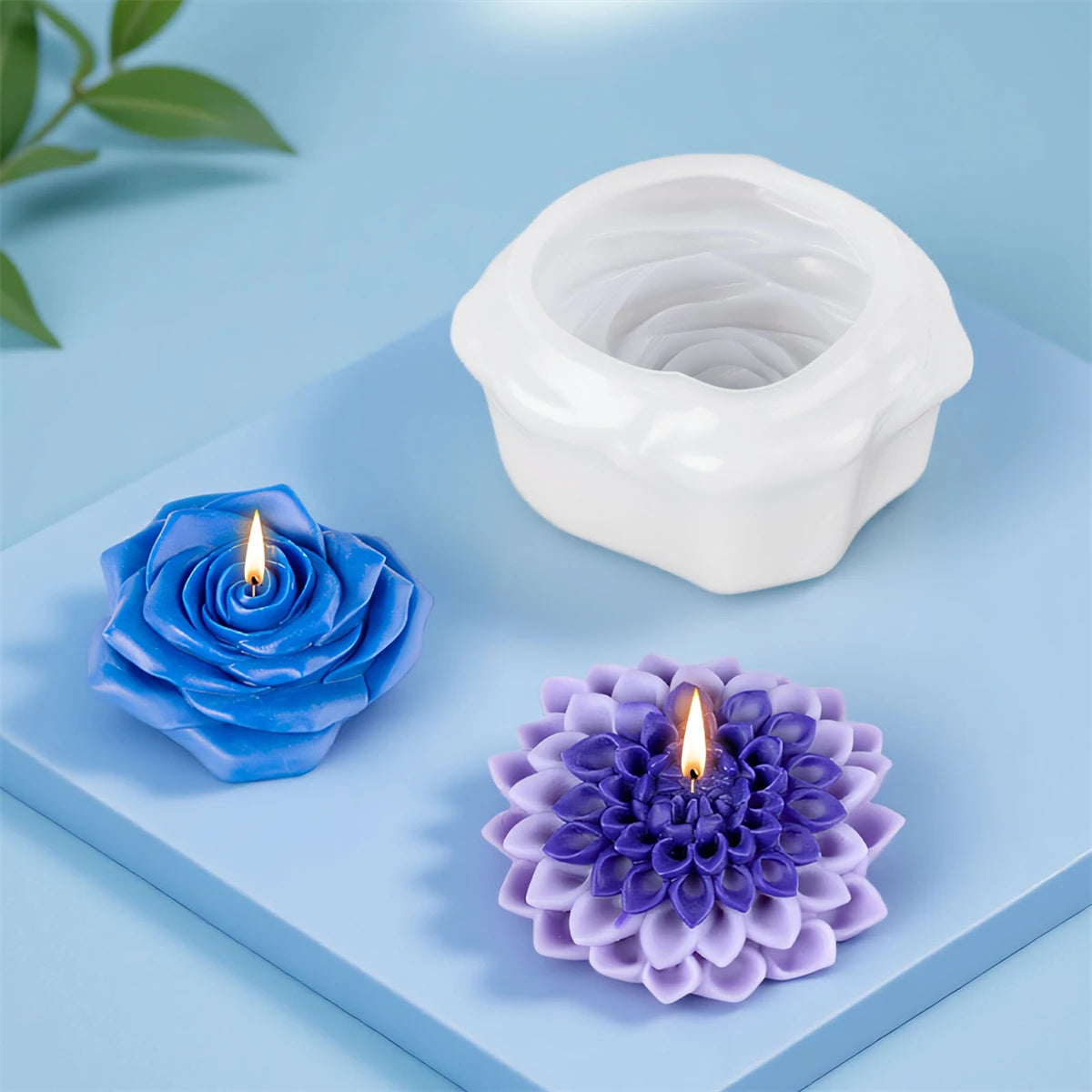 White silicone candle mold with a floral design and a purple silicone flower mold on a blue surface