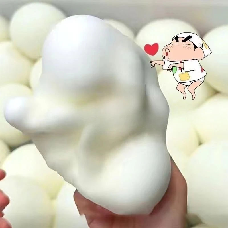 A hand holds a white squishy bread stress ball with a cartoon face, surrounded by many similar white toys.