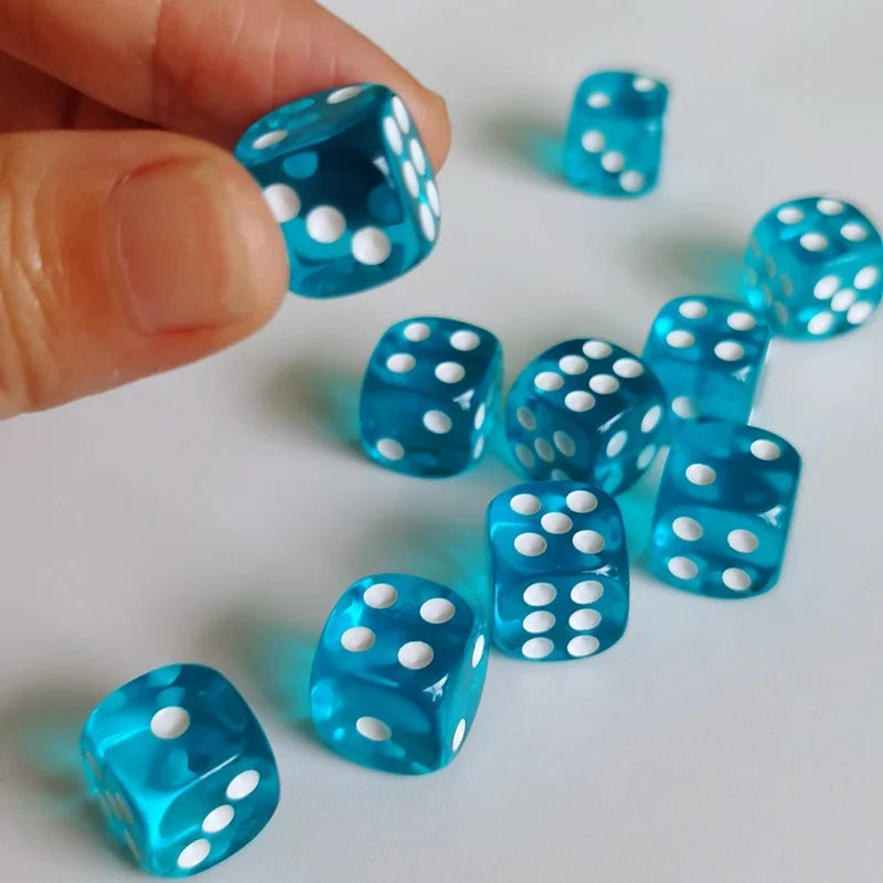 A hand holds a set of bright blue transparent dice with white polka dots on a white surface.