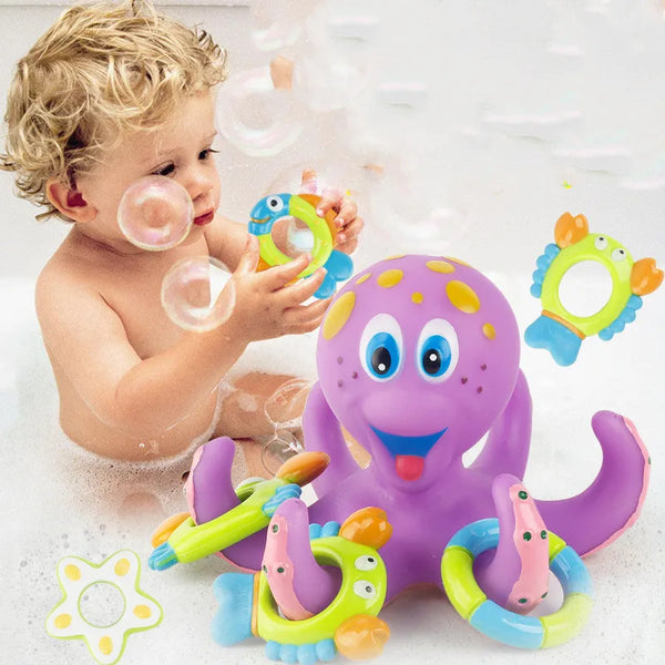 A baby is playing with a purple octopus bath toy and various colorful silicone rings in water.