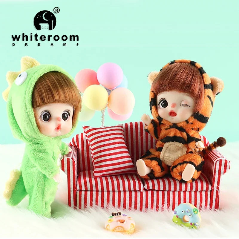 A fluffy green monster doll with large eyes sits next to a small orange and black tiger plush toy.