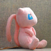 A soft pink Kawaii anime plush doll with blue eyes and a long pink ear is sitting on a light surface.