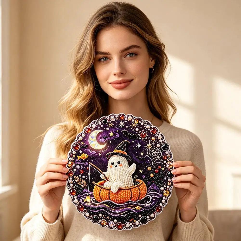 A woman holds a Halloween diamond painting ornament kit featuring a white ghost and a crescent moon on a dark purple backgrou