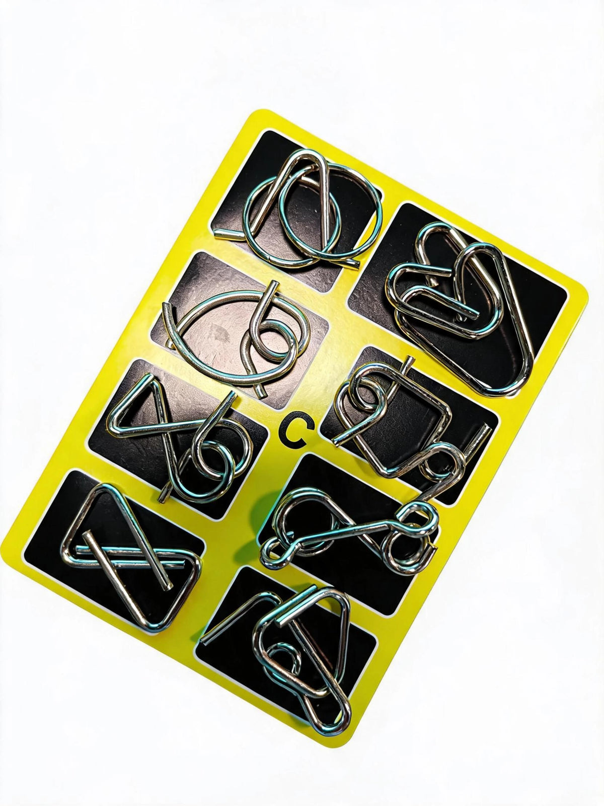 A yellow plastic tray holds eight metal brain teaser puzzle pieces for adults and teens.