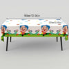 Table covered with a white cloth decorated with colorful circus clown figures and flowers for a party.