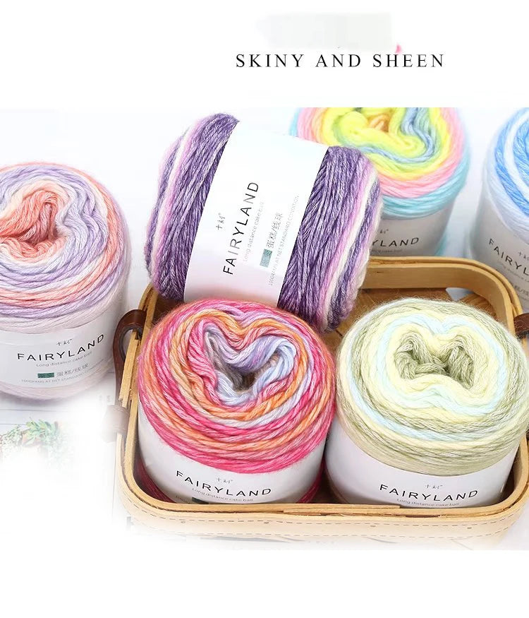 A collection of colorful gradient yarn spools in various shades of purple, pink, and yellow are displayed in a wooden box.