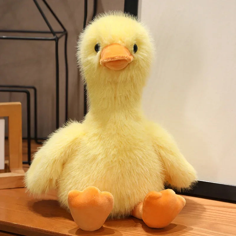 A yellow plush toy of a duck with orange feet is displayed on a wooden surface.