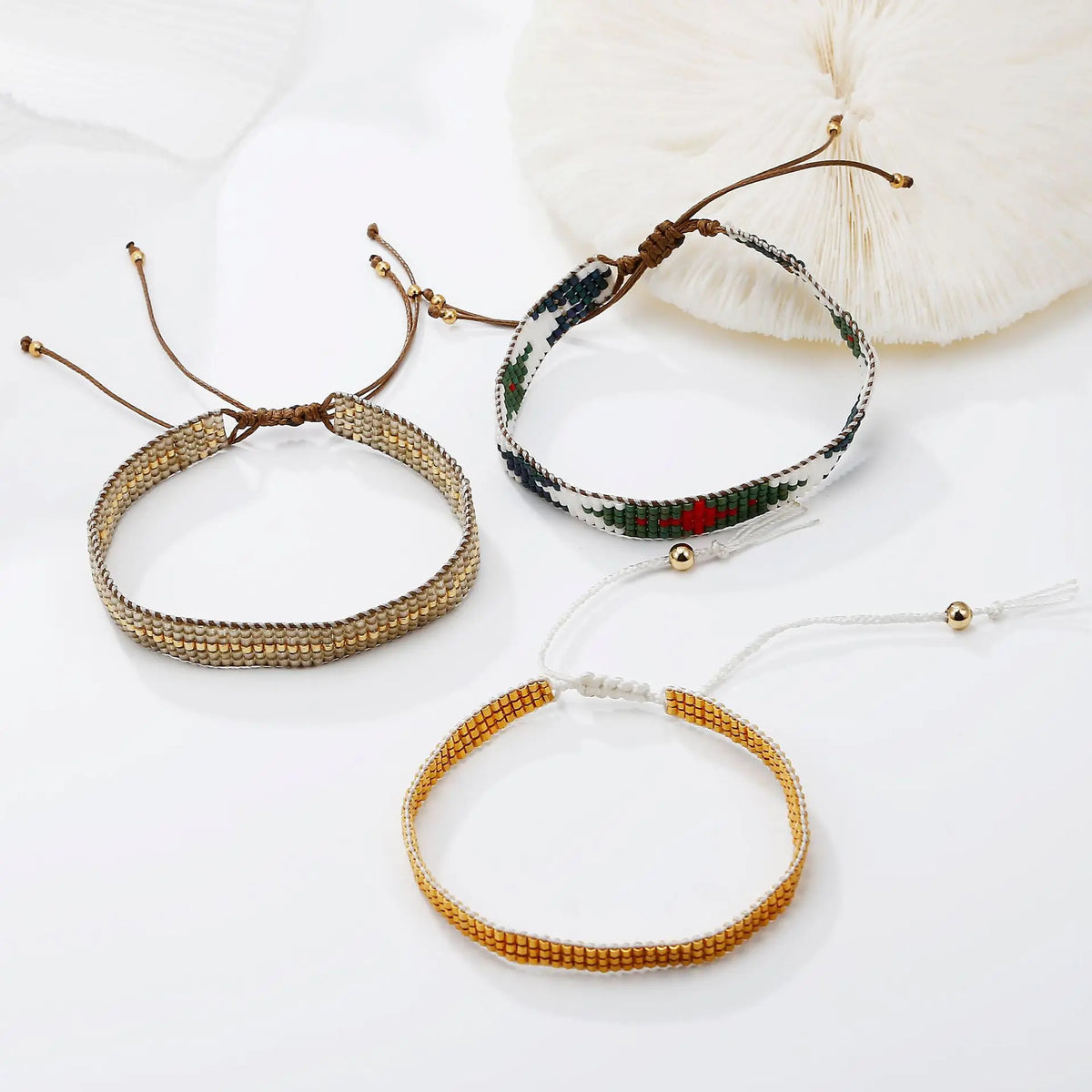 A collection of handcrafted jewelry bracelets and necklaces made with metallic glass beads, featuring gold, silver, and multi