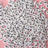 A close-up view of small white acrylic number beads scattered on a pink surface.