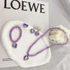 A set of five purple and silver princess jewelry accessories including necklaces and earrings displayed on a white plate.