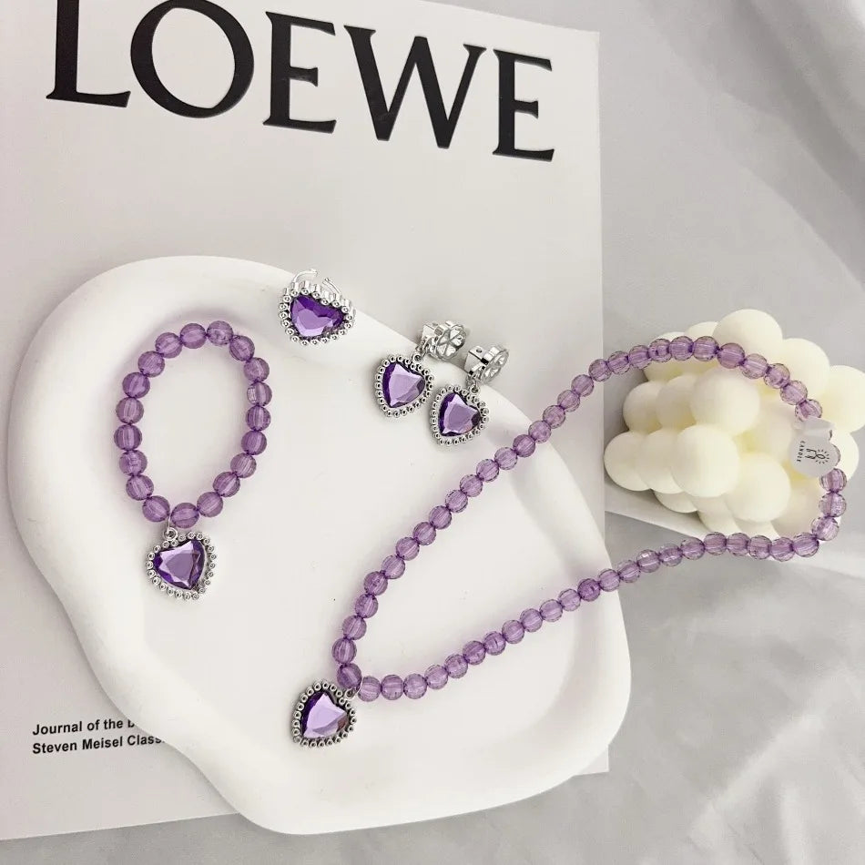 A set of five purple and silver princess jewelry accessories including necklaces and earrings displayed on a white plate.