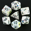 A set of white acrylic dice with colorful blood effects scattered on a dark surface.