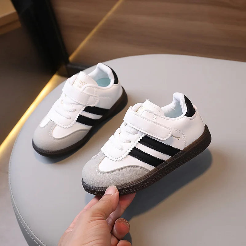 A pair of white and black casual sneakers resting on a light gray table surface.