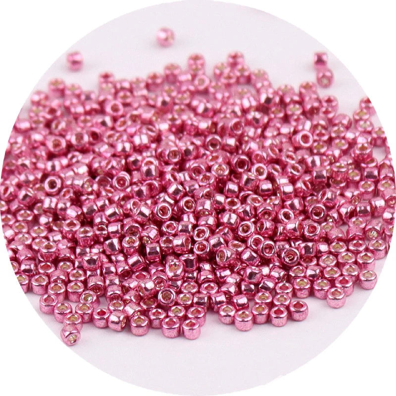 A pile of small, round metallic pink glass beads for jewelry making