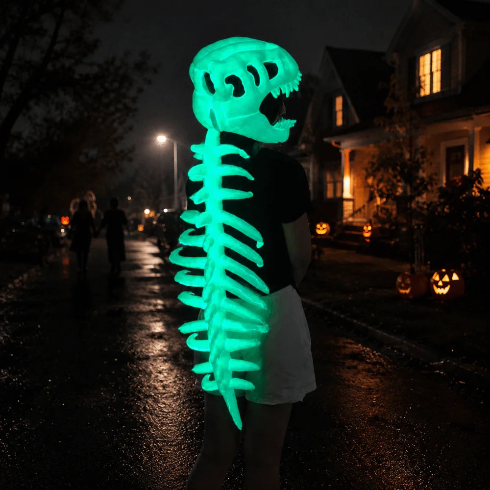 A person wearing a glow-in-the-dark dinosaur skeleton mask is walking down a dark, wet street at night.