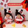 A pair of dark brown Monchhichi plush keychains with white fur and colorful accents are displayed on a light surface.