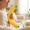 A woman is holding a bright yellow banana squishy stress relief toy.