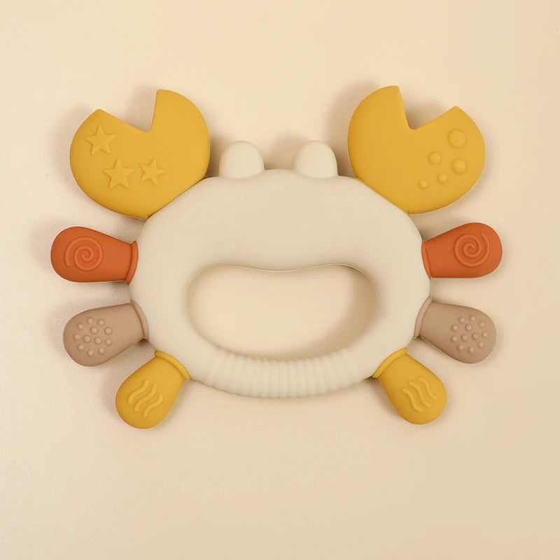 A yellow and orange crab-shaped silicone baby teether for soothing gums.