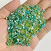 A handful of small, tumbled green and blue-green natural stone chips for jewelry making