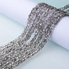 Silver faceted crystal beads strung together on a white background for jewelry making