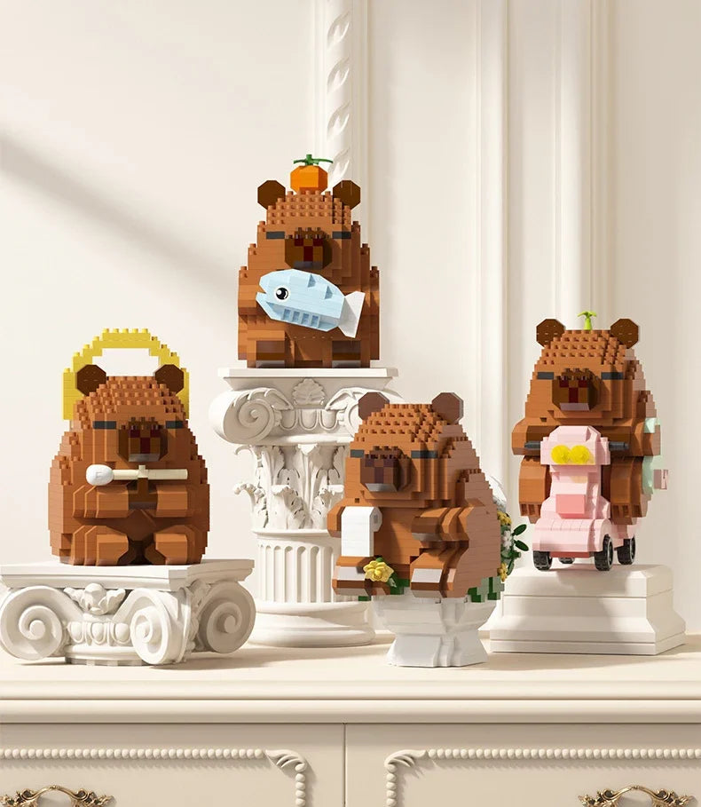 A set of cute desktop models made from brown and pink building blocks depicting a bear, a capybara, and a fish.