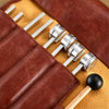 A set of tuning forks with metal strikers is displayed on a brown leather pouch.
