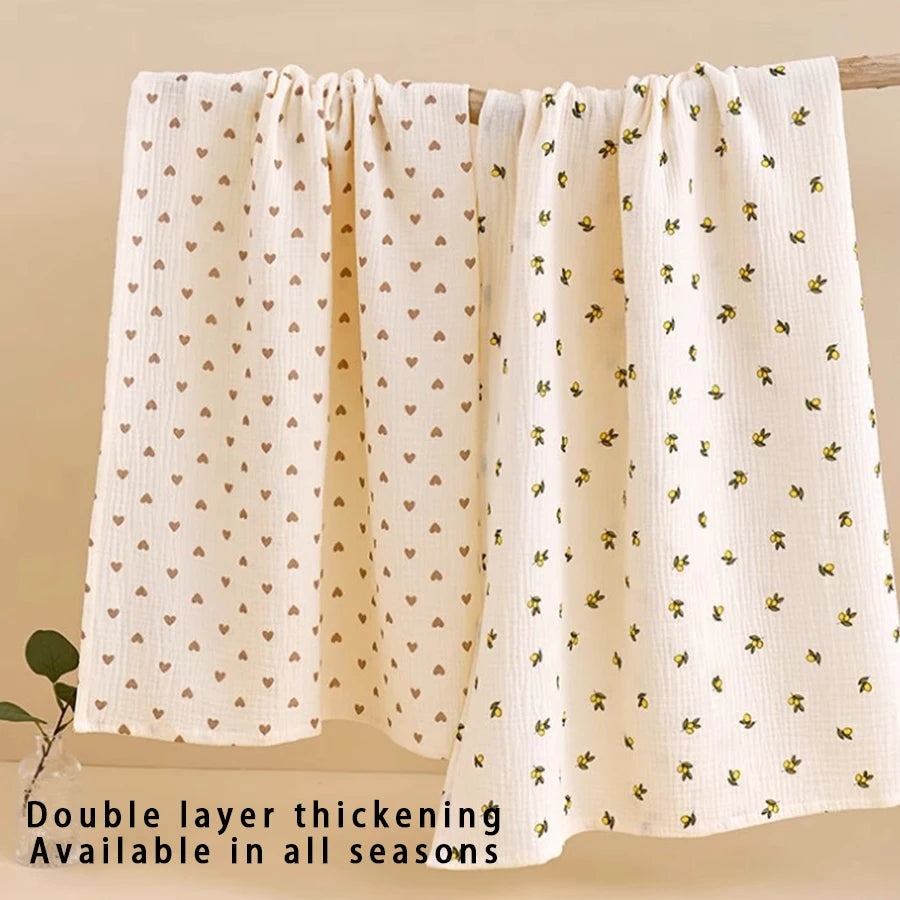 Two double layer thickening baby gauze swaddle blankets in cream with a yellow floral pattern hanging on a wooden rod.