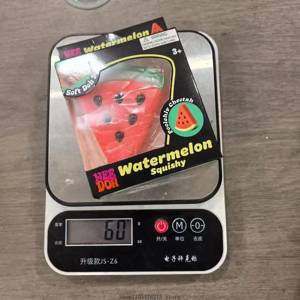 A package of watermelon squishy fidget toy with a warning label and a digital scale showing 60 oz.