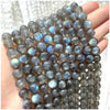 A hand holds a string of dark blue and gray natural stone beads for DIY jewelry making