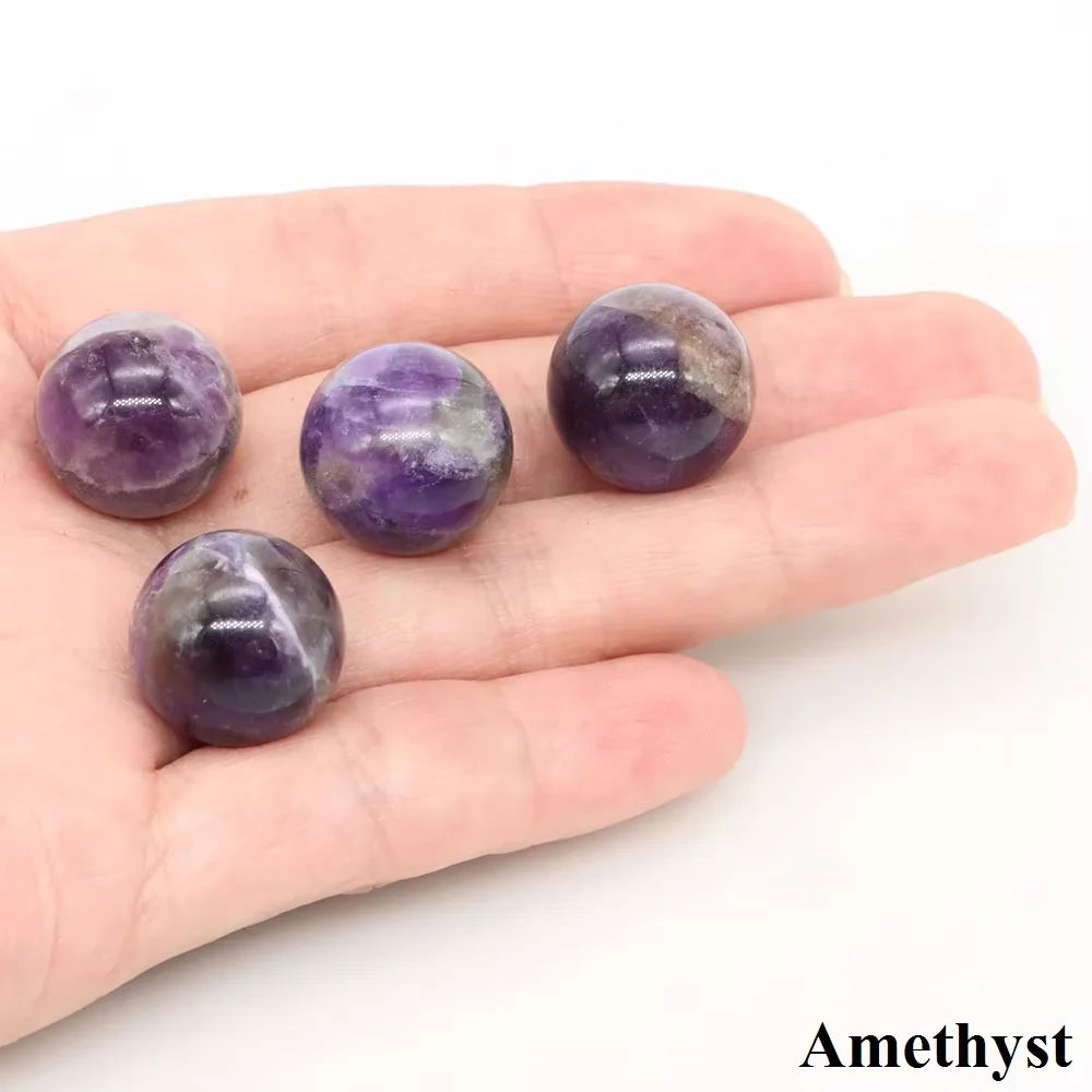 Five polished amethyst crystal spheres of varying shades are held in a person's hand.