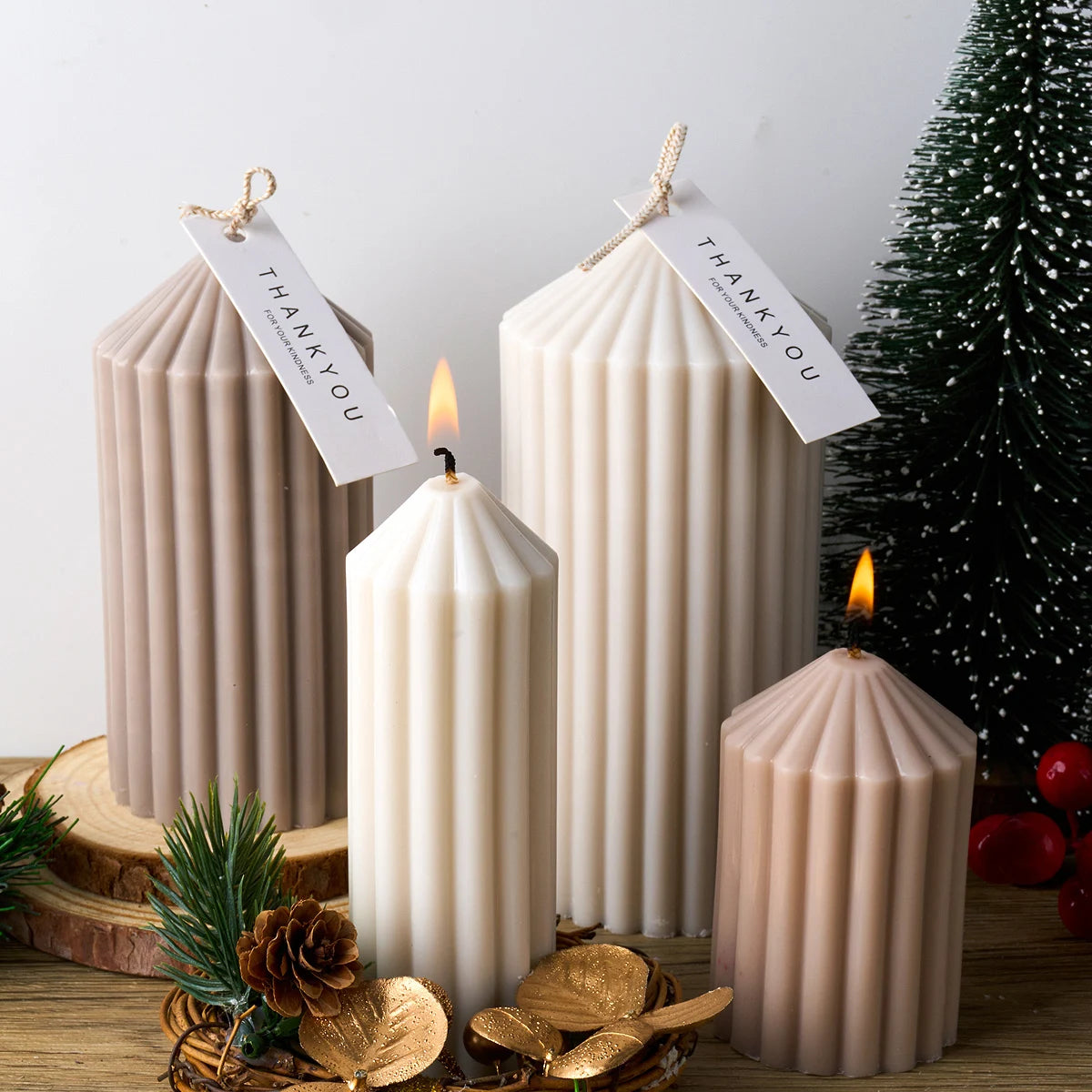 Three tall, cylindrical silicone candles in beige and white stripes with lit wicks displayed on a wooden surface.