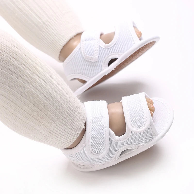 White breathable first walker sandals for baby, shown on a leg.