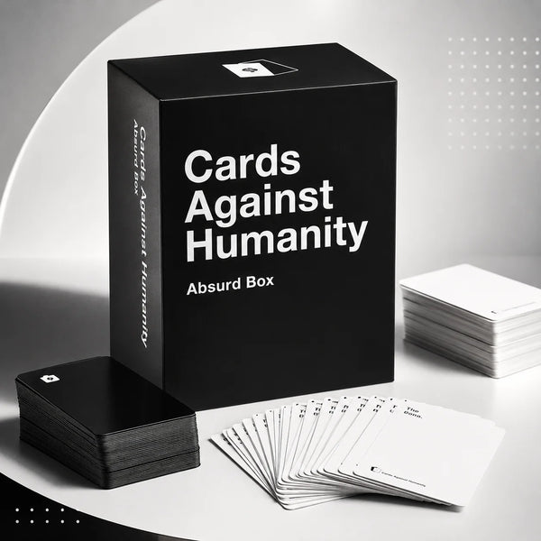 A black box of Cards Against Humanity Absurd Box with several cards laid out on a white surface.