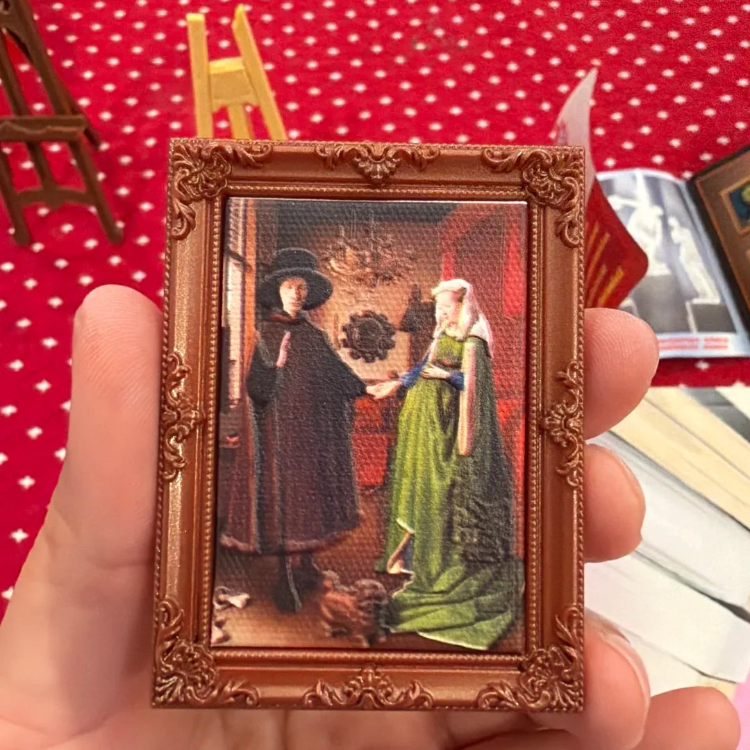 A small framed picture featuring two figures in historical attire, likely a blind ball from the Zuru Mini Brands Create Maste