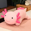 A pink axolotl plush pillow with pink gills resting on a light pink surface.