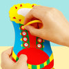 Eine Hand führt einen gelben Seil durch Löcher in ein farbiges, handförmiges Spielzeug für frühe Bildung und Feinmotorik.