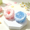 Pink and blue squishy sensory stress balls resting on a white hexagonal block with scattered star-shaped confetti.