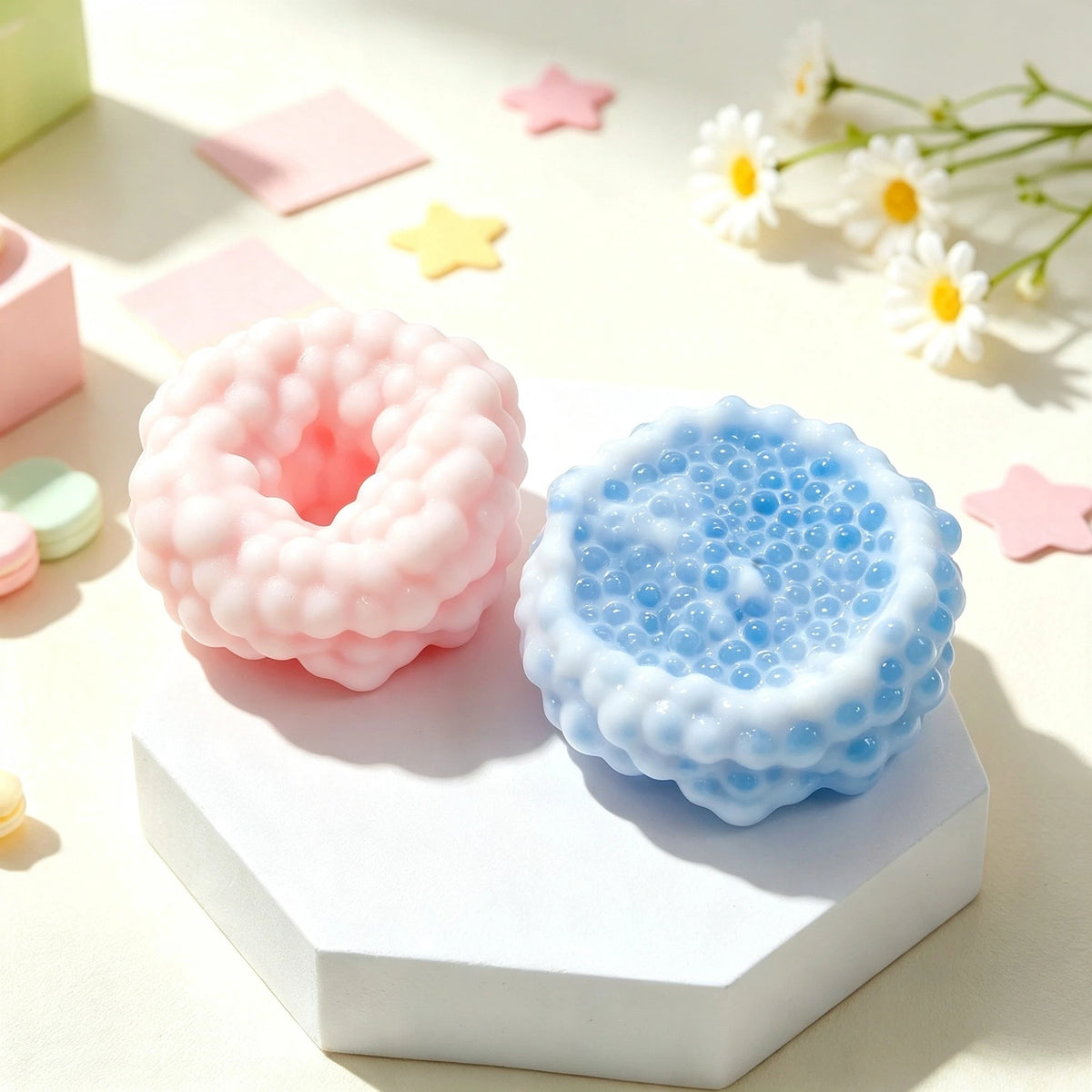Pink and blue squishy sensory stress balls resting on a white hexagonal block with scattered star-shaped confetti.