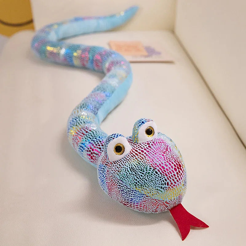 A colorful, iridescent blue and purple cartoon snake plush toy with large eyes resting on a white surface.