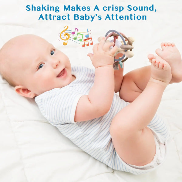 A smiling baby is holding a silicone rattle and sensory ball, which makes a crisp sound.