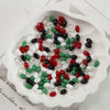 Oval glass rice grain beads in various colors including red green black white and clear are displayed in a white dish