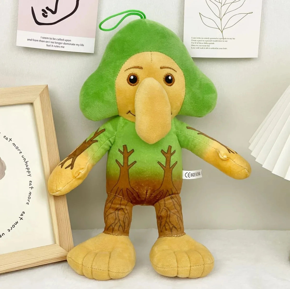 A soft green and tan plush toy shaped like a shark with large eyes and floppy limbs.