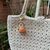 A handcrafted crochet animal keychain in a light beige color with a gold-toned metal loop.