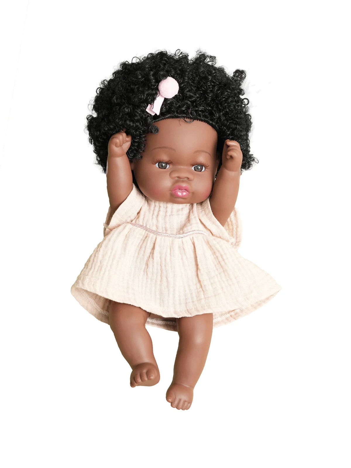 A dark-skinned baby doll with curly hair wearing a cream-colored, textured outfit and a pink bow.